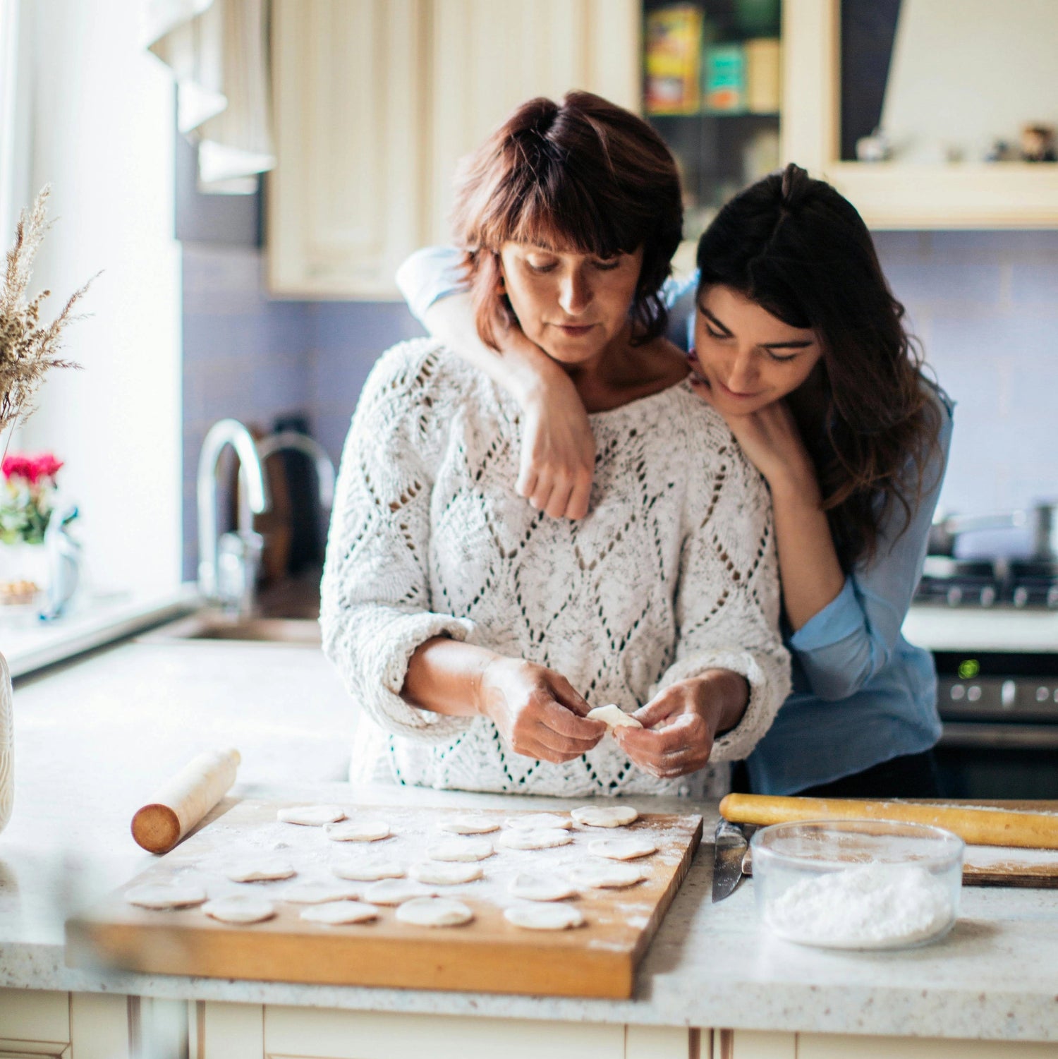Two women in a kitchen making cookies.